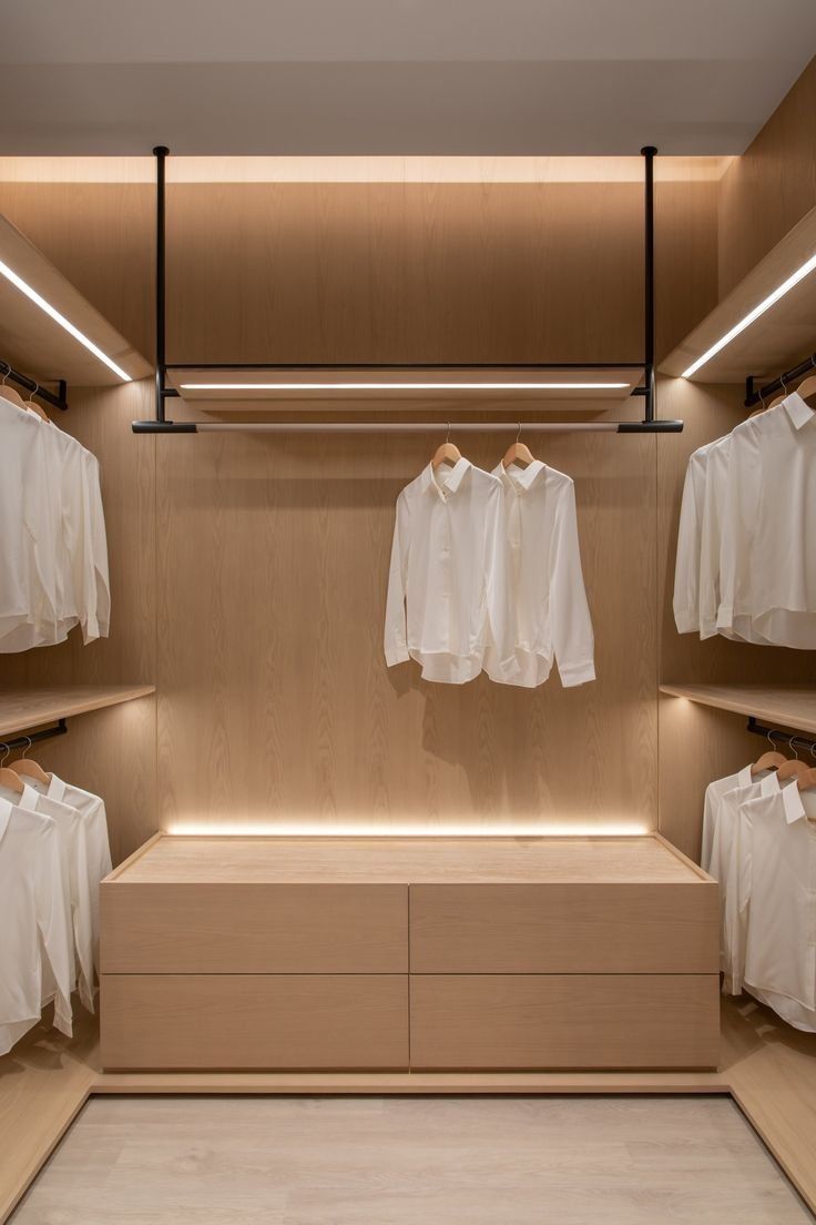 Minimalist wooden walk-in closet with cove lighting and central drawer unit | Al Janah Al Malaky