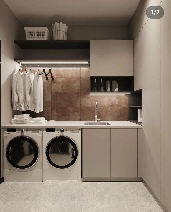 Contemporary laundry room with side-by-side washers, utility sink, and rusted tile backsplash | Al Janah Al Malaky