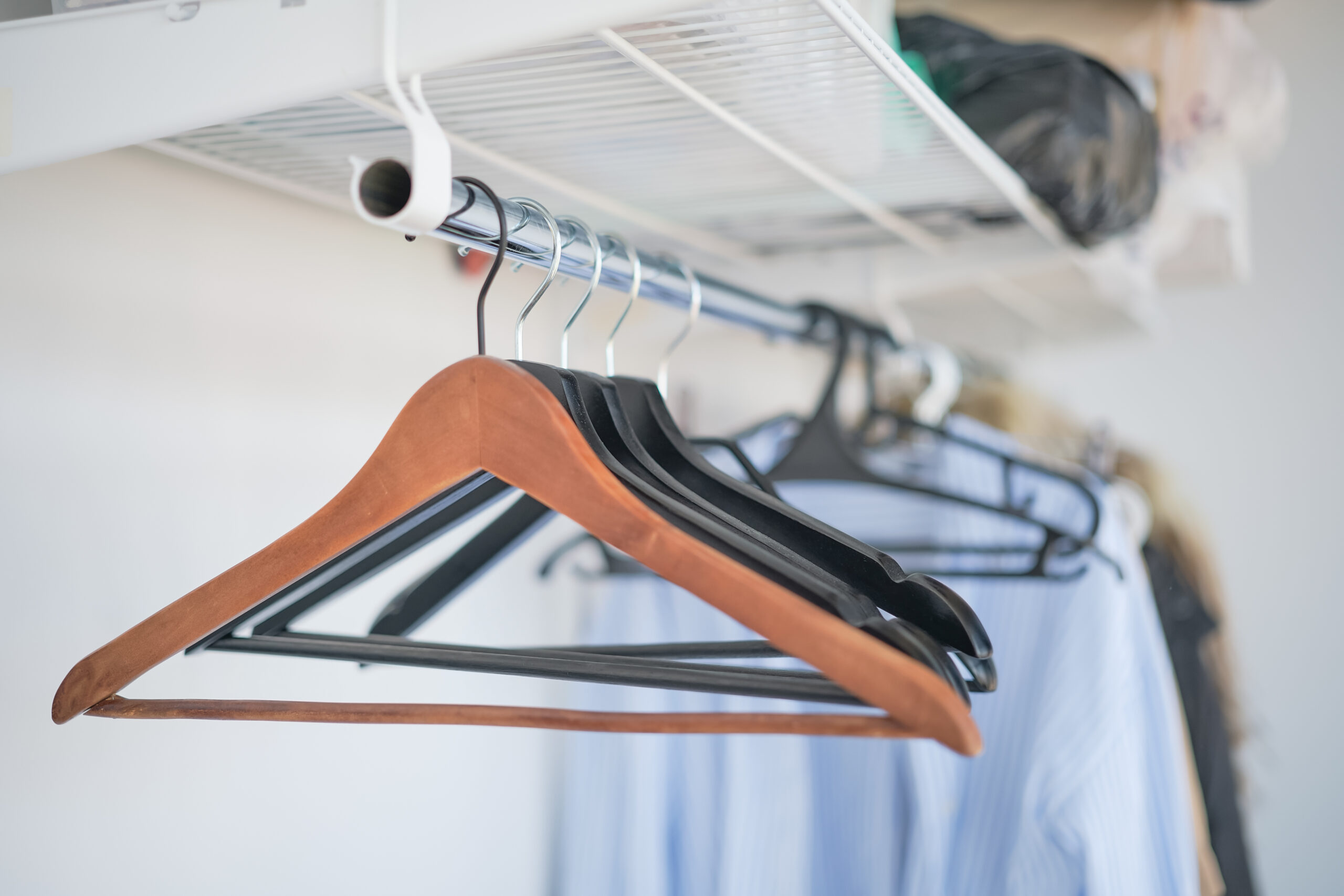 Wooden and plastic clothes hangers hanging in a closet | Al Janah Al Malaky